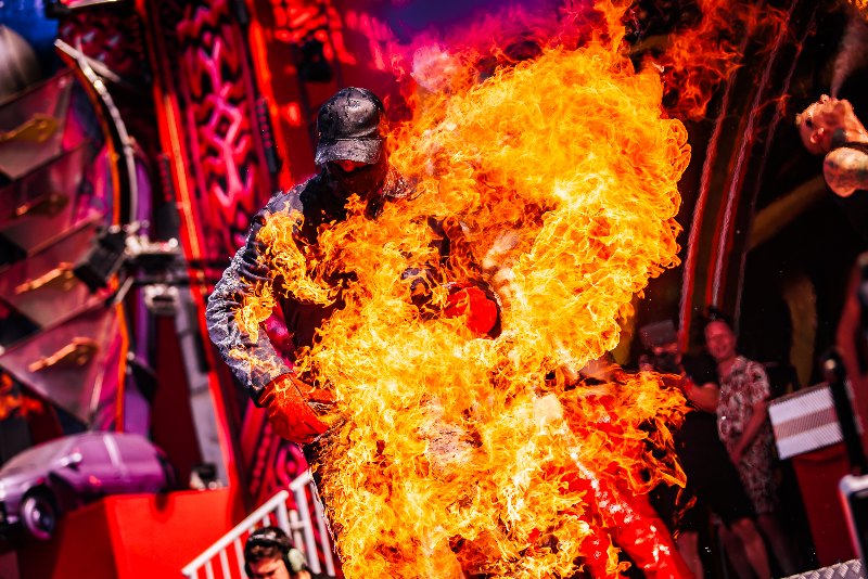 Stuntman in protective gear engulfed in flames in front of a red festival stage