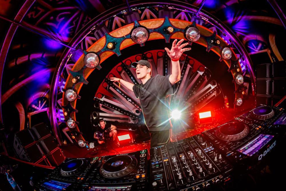 DJ with raised arms inside a circular LED stage at Defqon.1