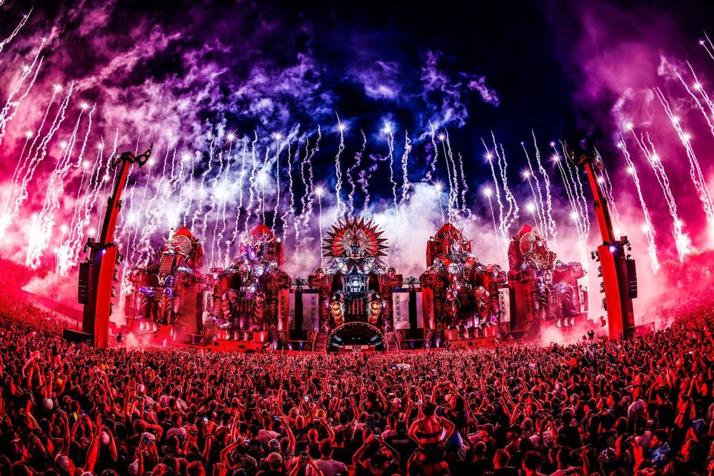 Defqon.1 stage with fireworks and light beams over the crowd