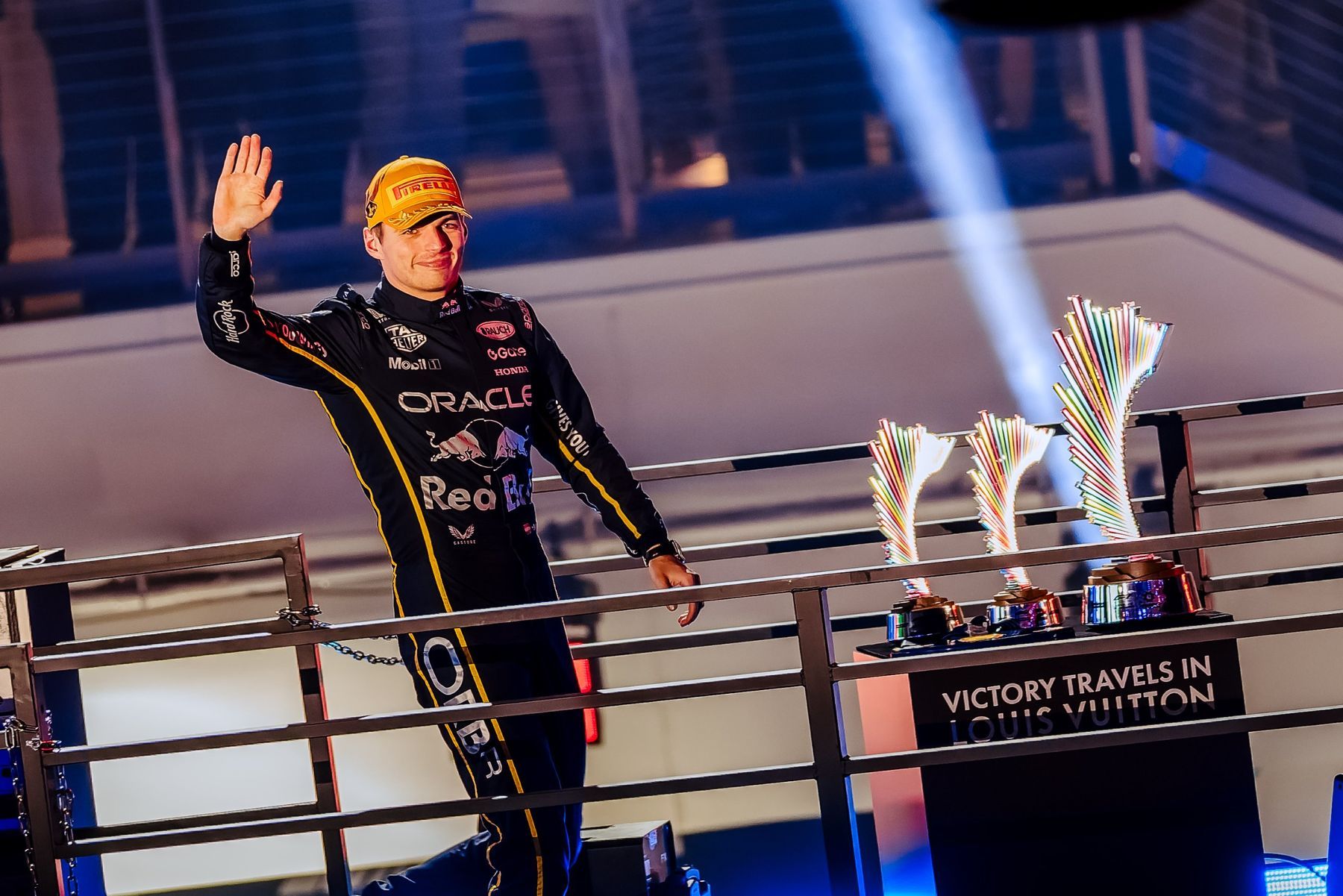 Formula 1 driver waving two trophies on the podium