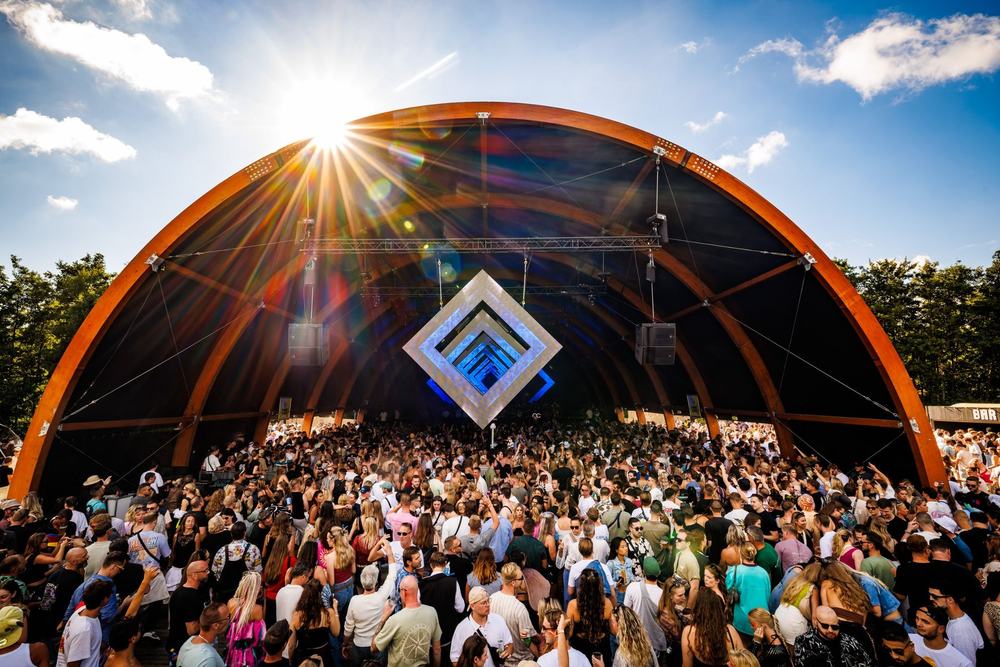 Festival arch stage with the sun bursting over the crowd