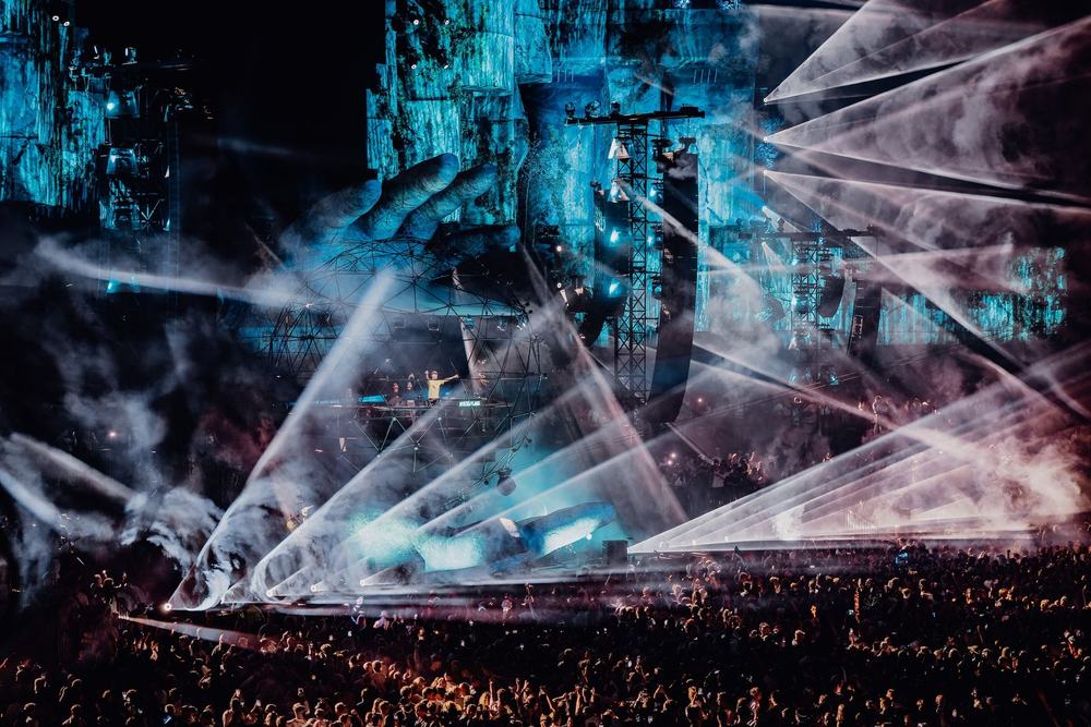 Mysteryland stage with blue lasers cutting through smoke